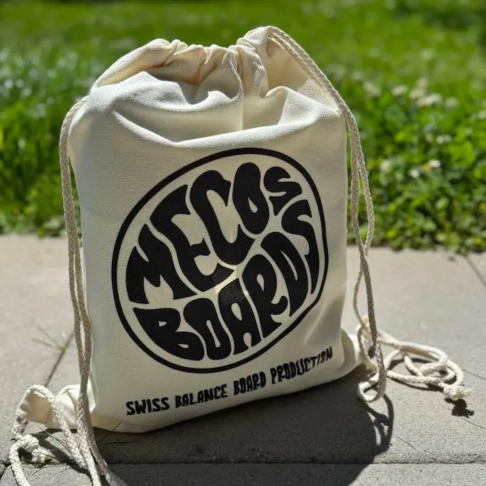 Daily Cotton Bag von Mecos Boards aus Naturbaumwolle mit grossem Logo-Print – steht auf sonnigem Untergrund.