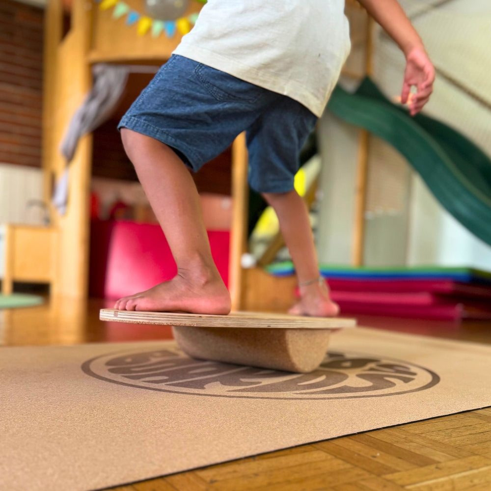 Kind balanciert sicher auf Mini Balance Board von Mecos Boards mit Korkrolle im Wohnzimmer