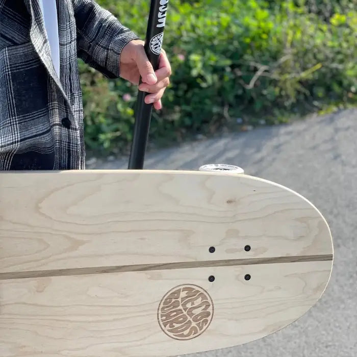 Mann hält das MECOS BOARDS Land Paddle und ein Longboard mit sichtbarem Logo