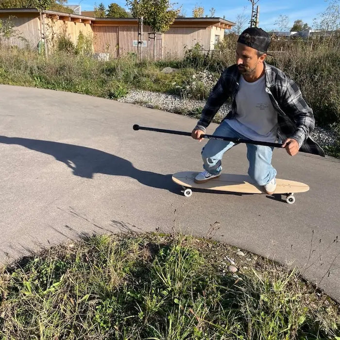Mann beim dynamischen Carven auf einem Longboard mit dem MECOS BOARDS Land Paddle