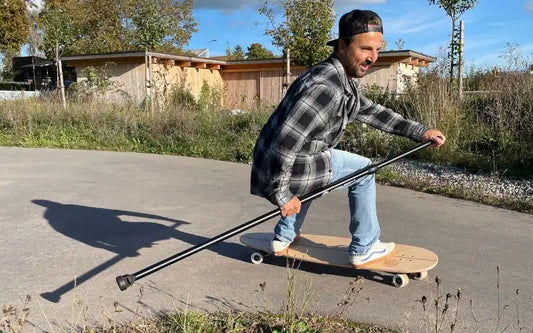 Fahrer surft mit dem Land-Surfer Longboard und Paddle über den Asphalt