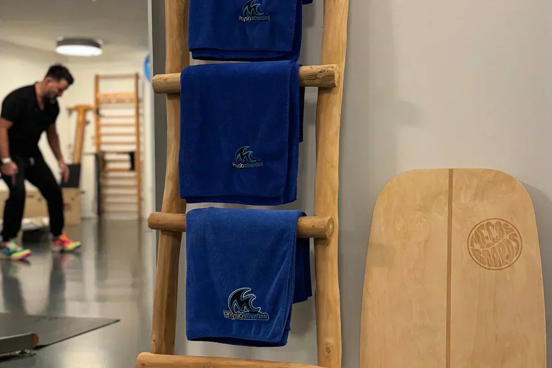 Handtücher der Praxis Physio Atlântico an einer Holzleiter, daneben der Motion Rocker von Mecos Boards in der Physiotherapie.