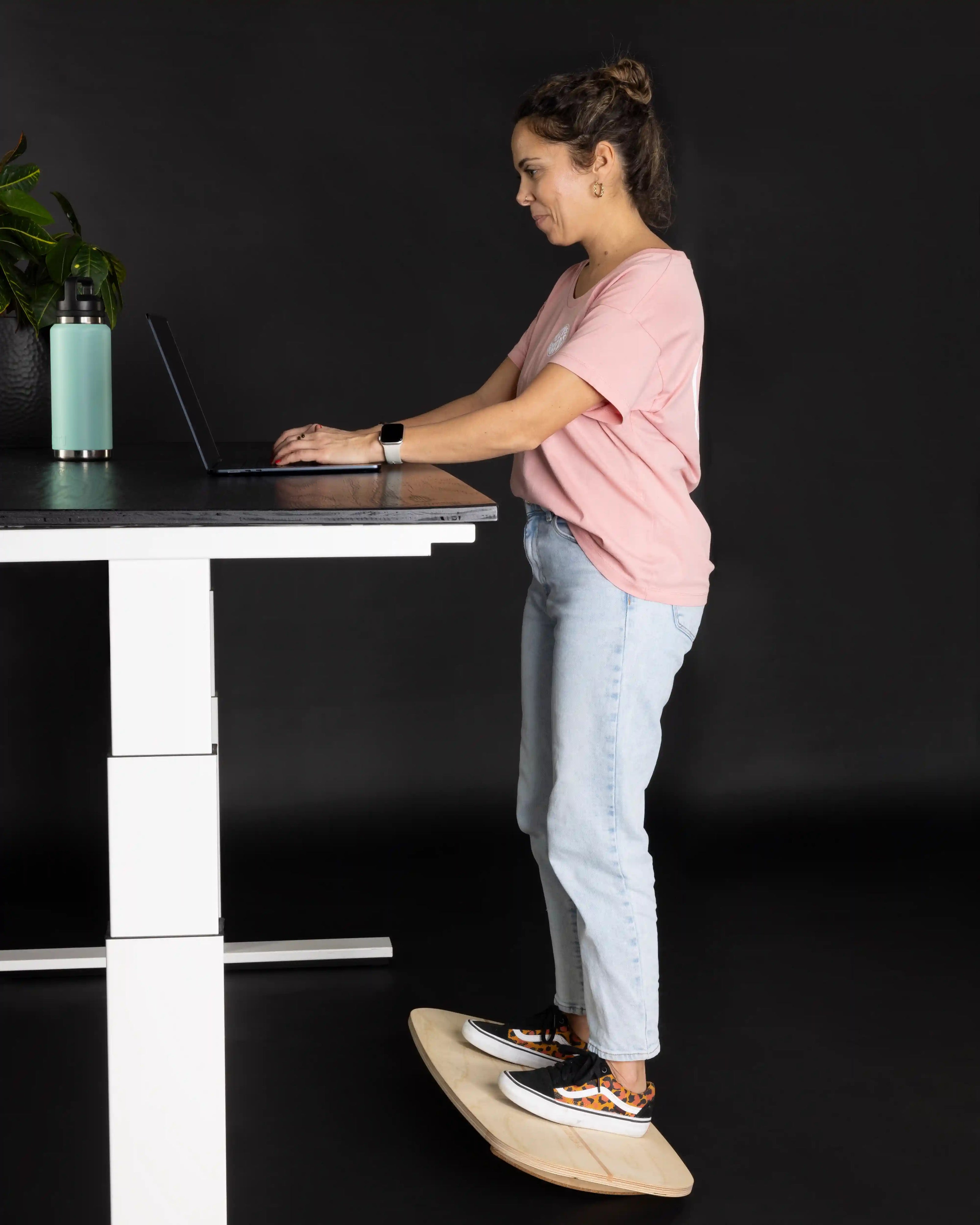 Frau steht auf MECOS BOARDS Motion Rocker Balance Board am Stehpult – aktives Arbeiten im Büro