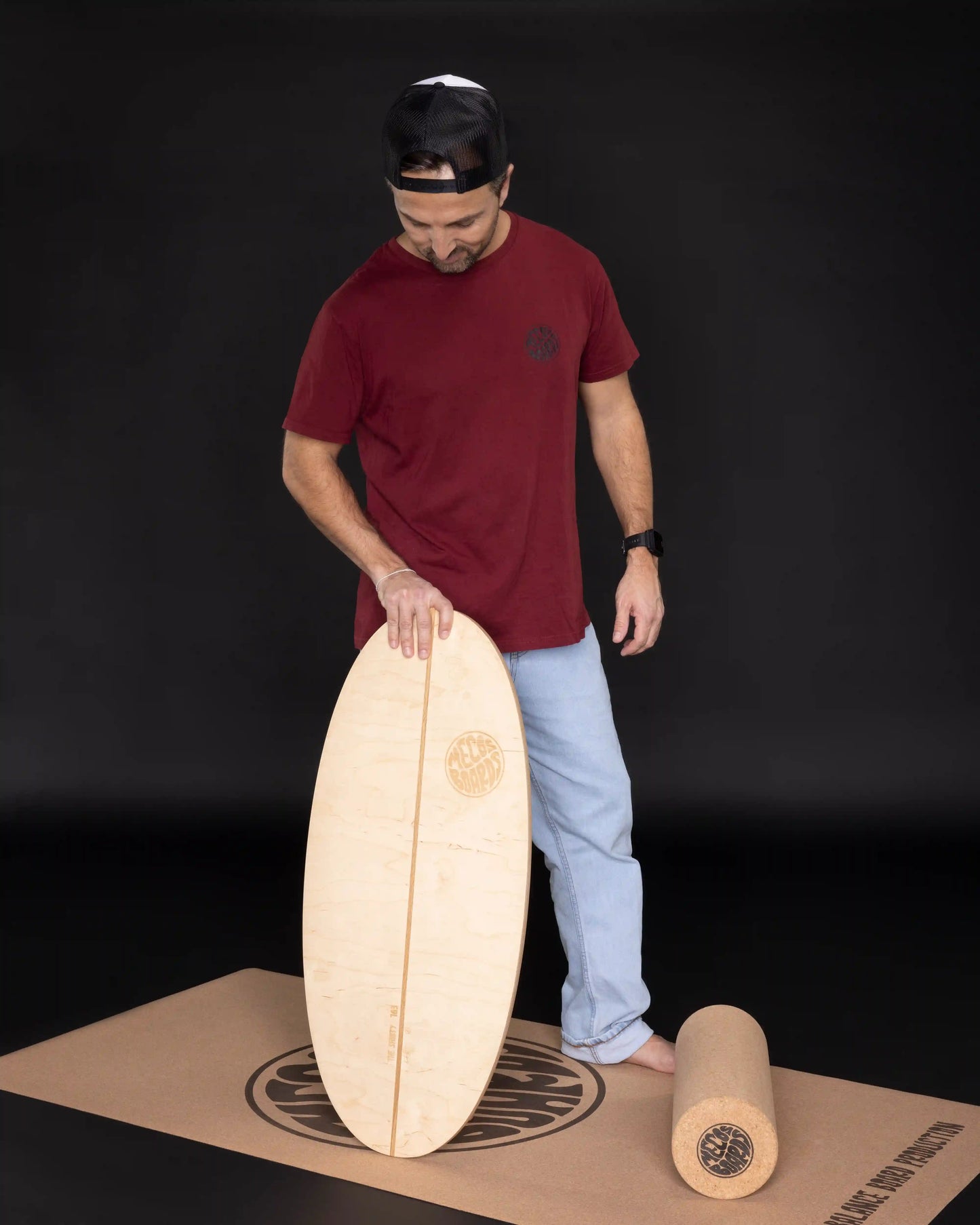 Mann steht und hält MECOS BOARDS Shorty Balance Board – schwarzer Hintergrund