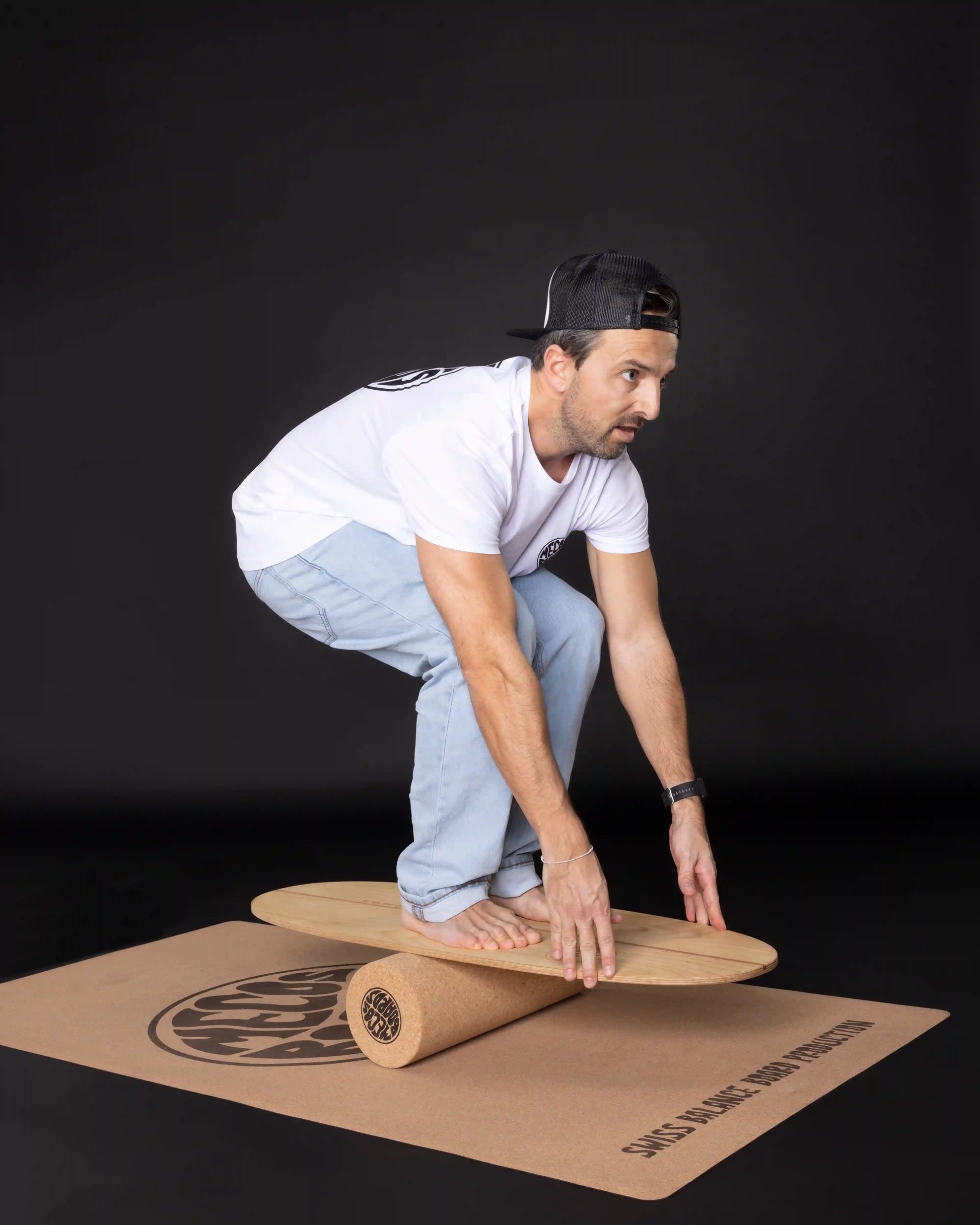 Mann greift mit beiden Händen ans MECOS BOARDS Twin-Tipper Balance Board – Grab-Trick auf Korkrolle