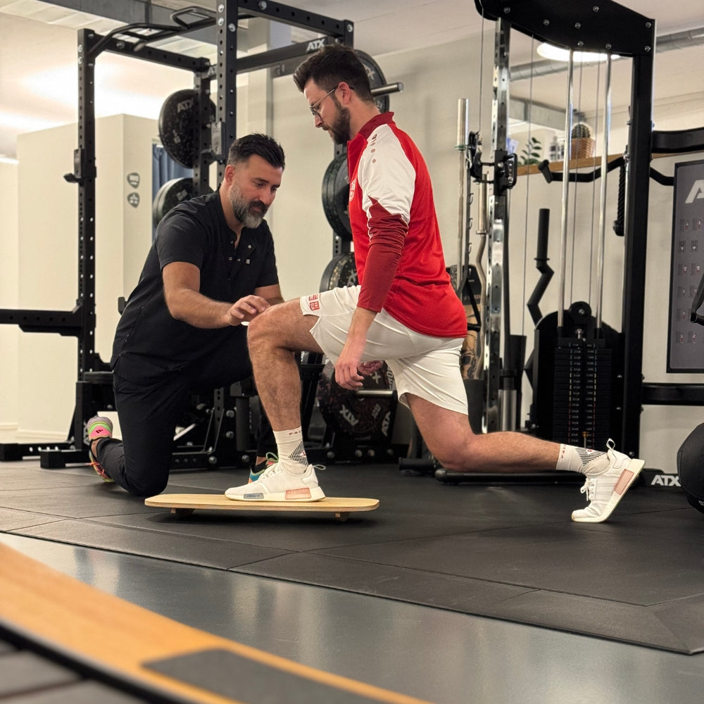 Ausfallschritt auf dem Motion Rocker in der Physiotherapie – Anleitung durch den Therapeuten zur Verbesserung von Gleichgewicht und Beinachsenstabilität.