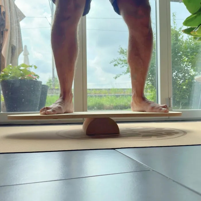 Anfänger trainiert barfuss mit THE SHORTY Balance Board auf halber Korkrolle – Balance Training auf Korkmatte im Wohnzimmer.